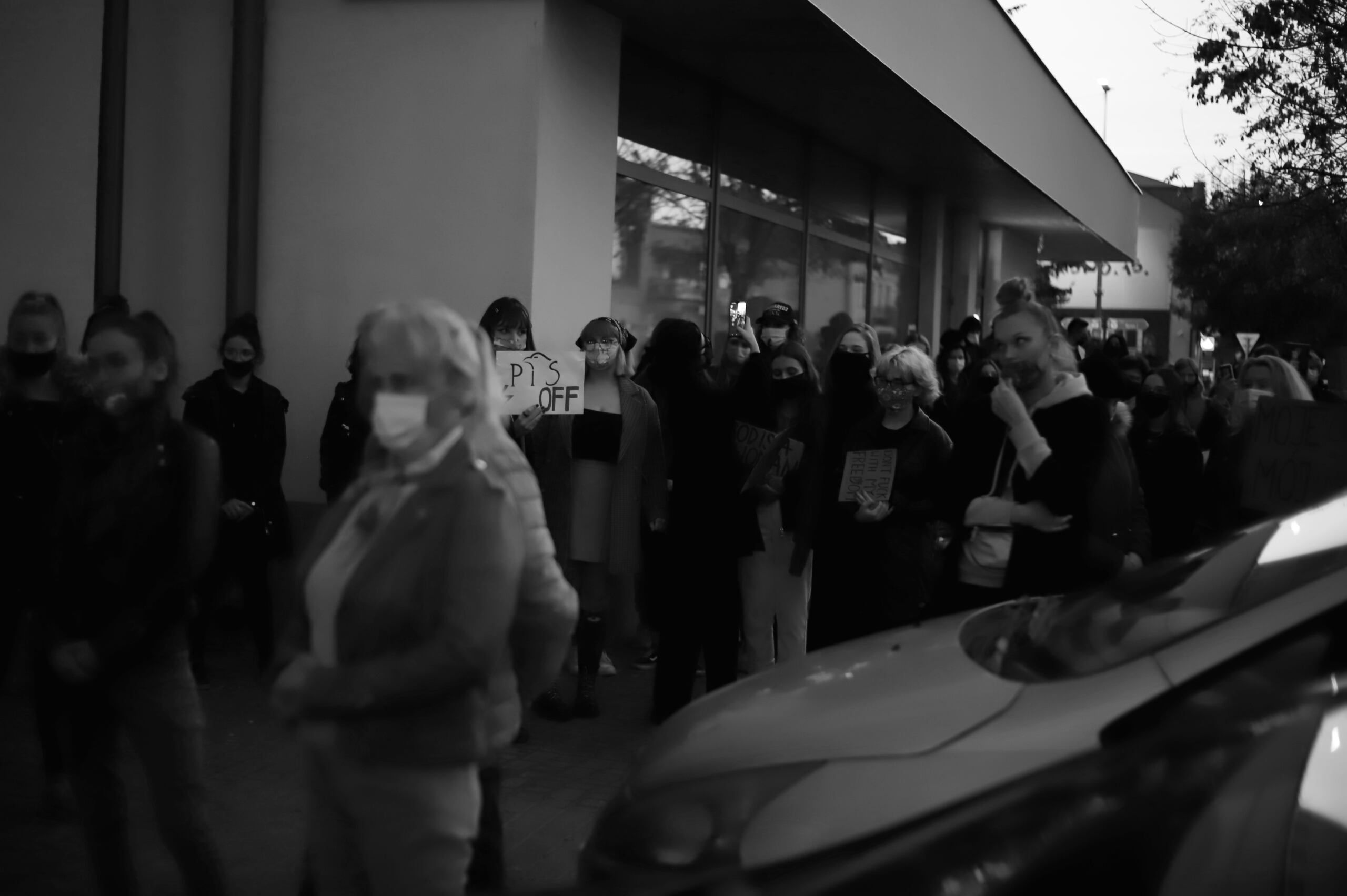 Grupa ludzi idąca chodnikiem. Zdjęcie czarno-białe