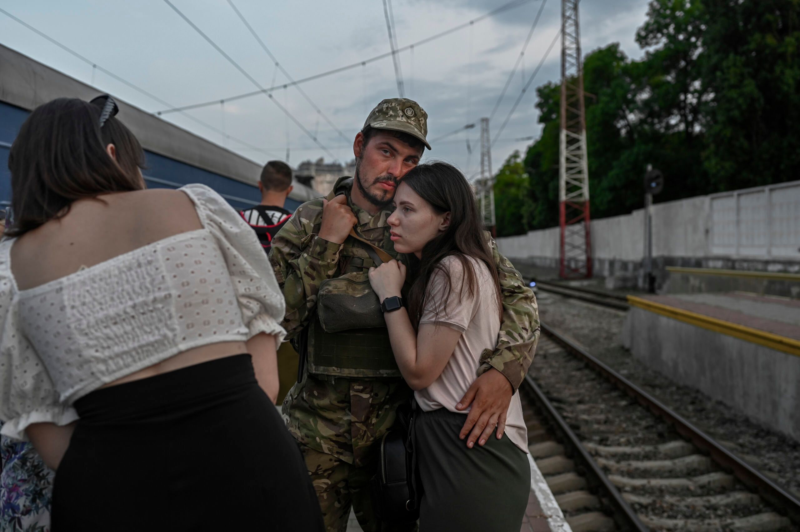 A Ukrainian soldier hugs his partner prior to board a train to Dnipro at the train station of Odessa on July 24, 2022 amid the Russian invasion of Ukraine. (Photo by BULENT KILIC / AFP)