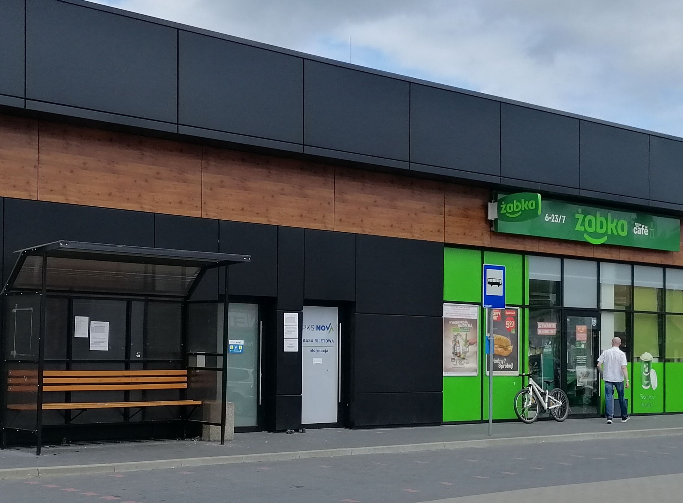 Budynek, w niszy ławka, na ścianie tablica kursów