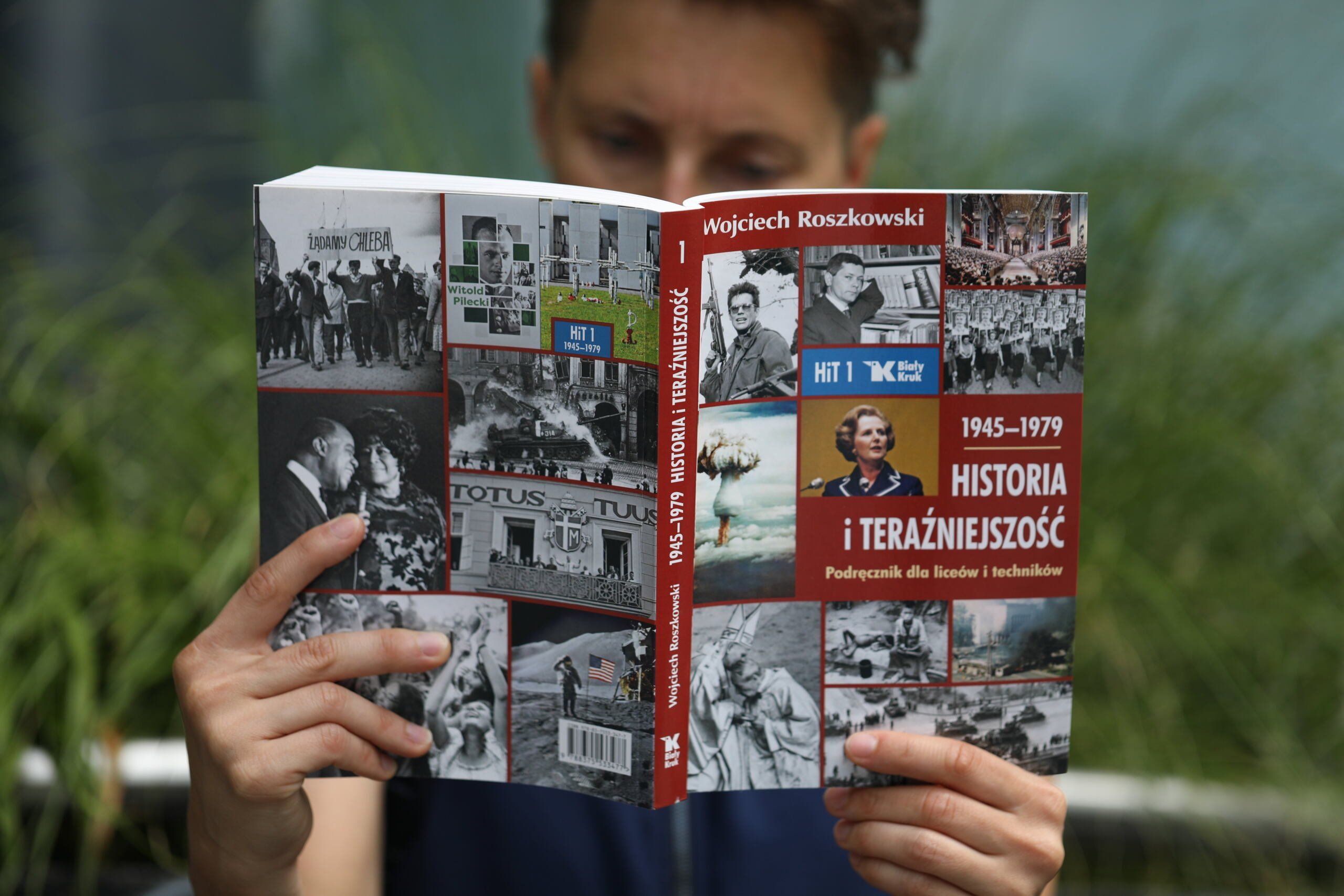 Młody człowiek czyta podrecznik Roszkowskiego do HiT