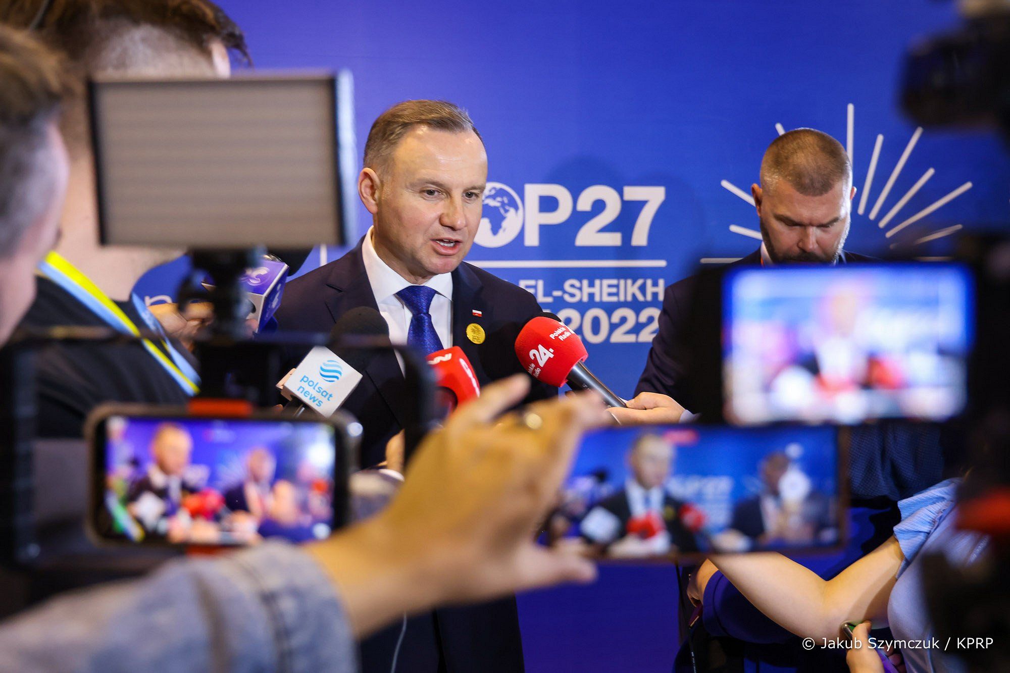 Prezydent Duda rozmawia z dziennikarzami na tle wielkiego napisu COP27