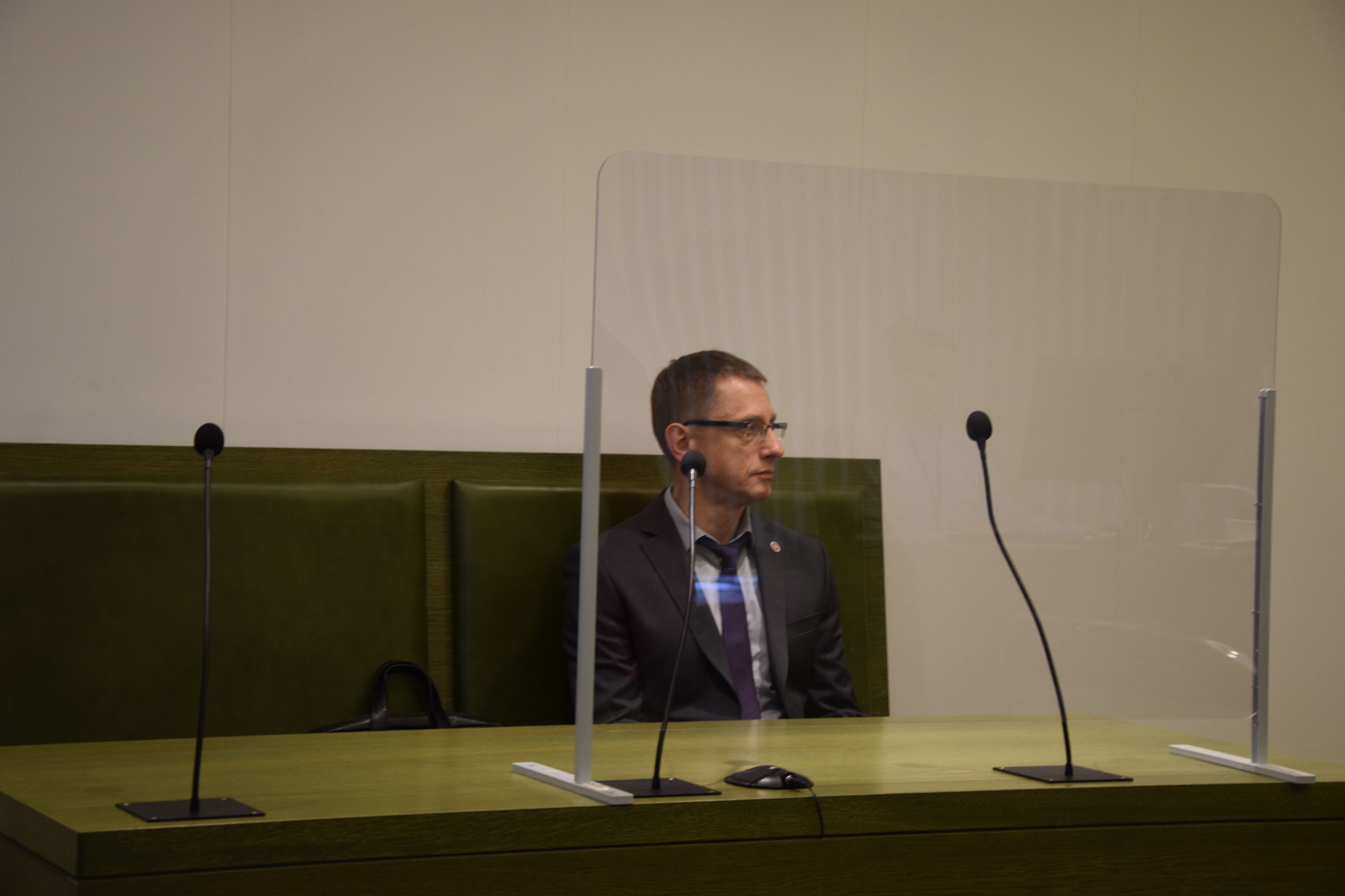 Mężczyzna w garniturze siedzi na ławie w sądzie