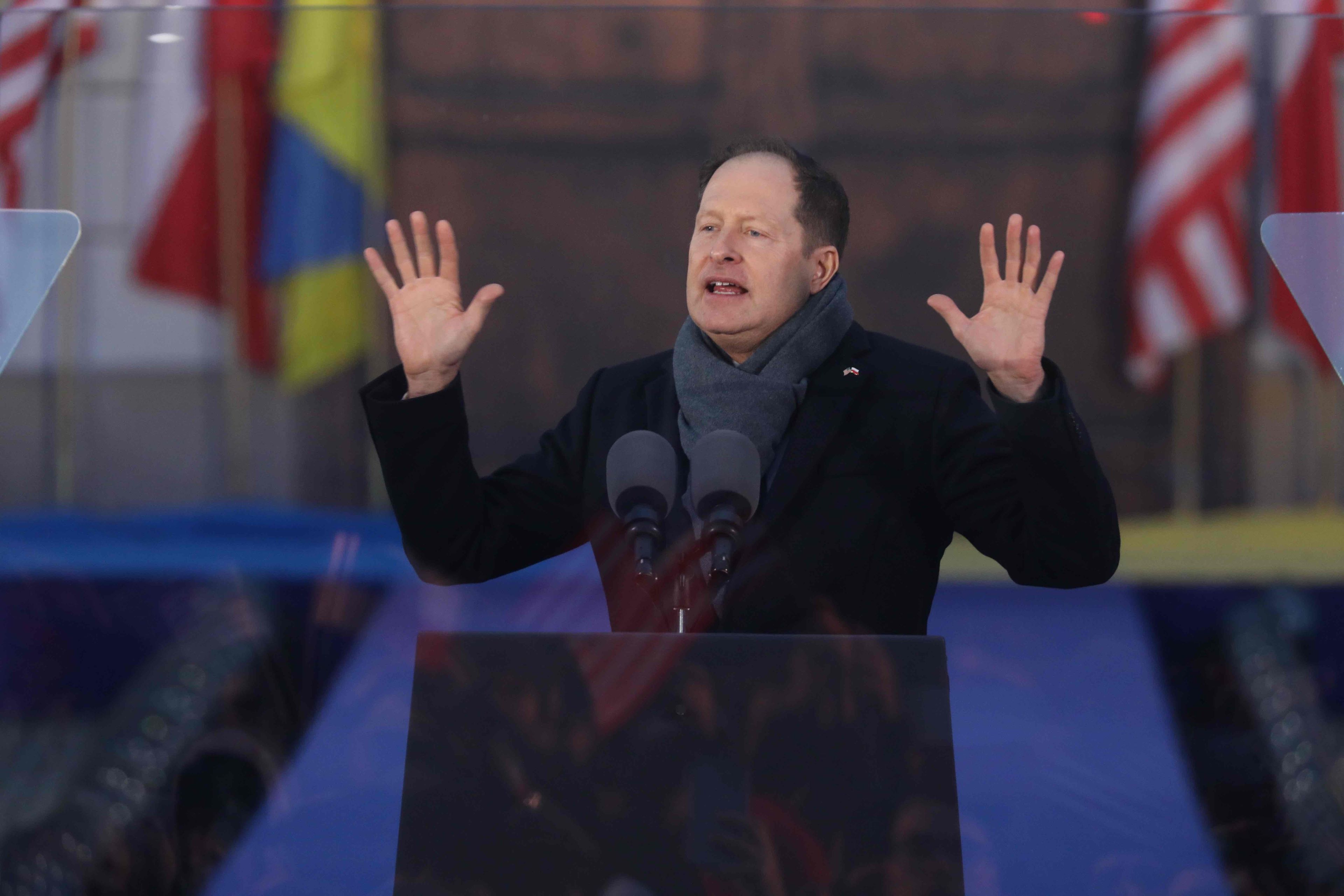 Ambasador USA Mark Brzeziński przemawia pod Zamkiem Królewskim z podniesionymi do góry rękoma.