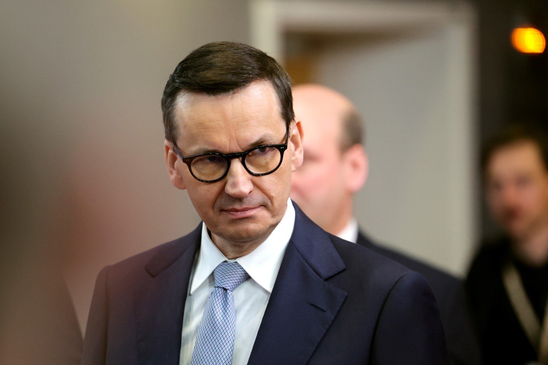 Premier Morawiecki patrzy w bok z groźną albo smutna miną