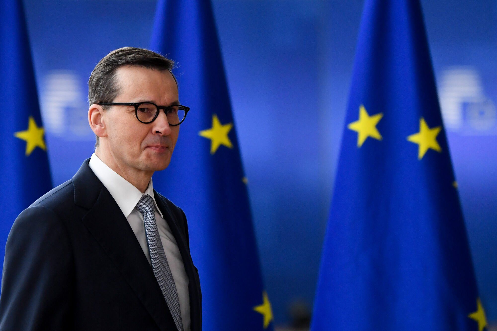 Premier Mateusz Morawiecki na tle unijnej flagi zmierza na posiedzenie Rady Europejskiej w Brukseli 23 marca 2023 roku