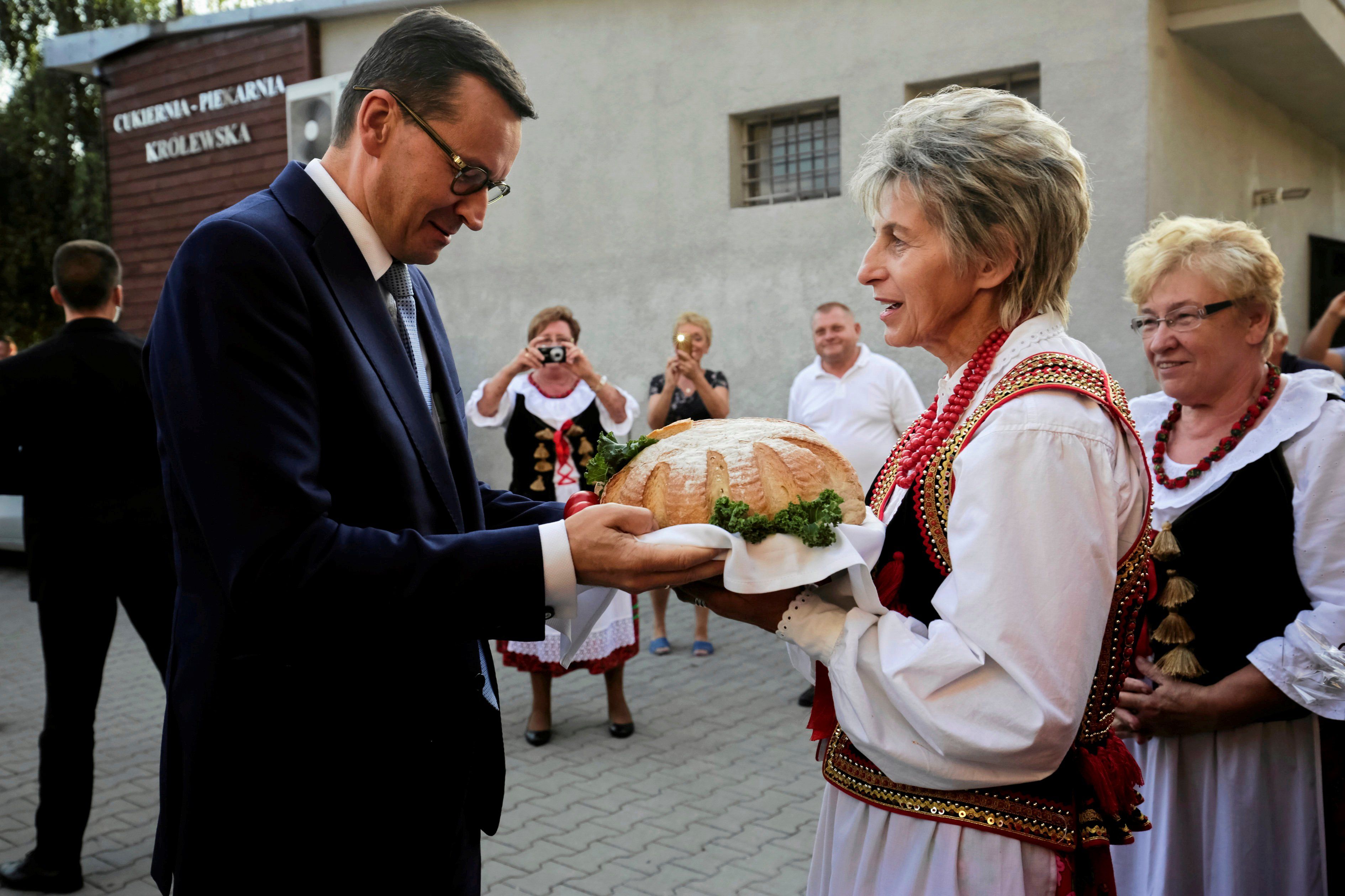 Mężczyzna przymuje chleb od kobiety w stroju ludowym