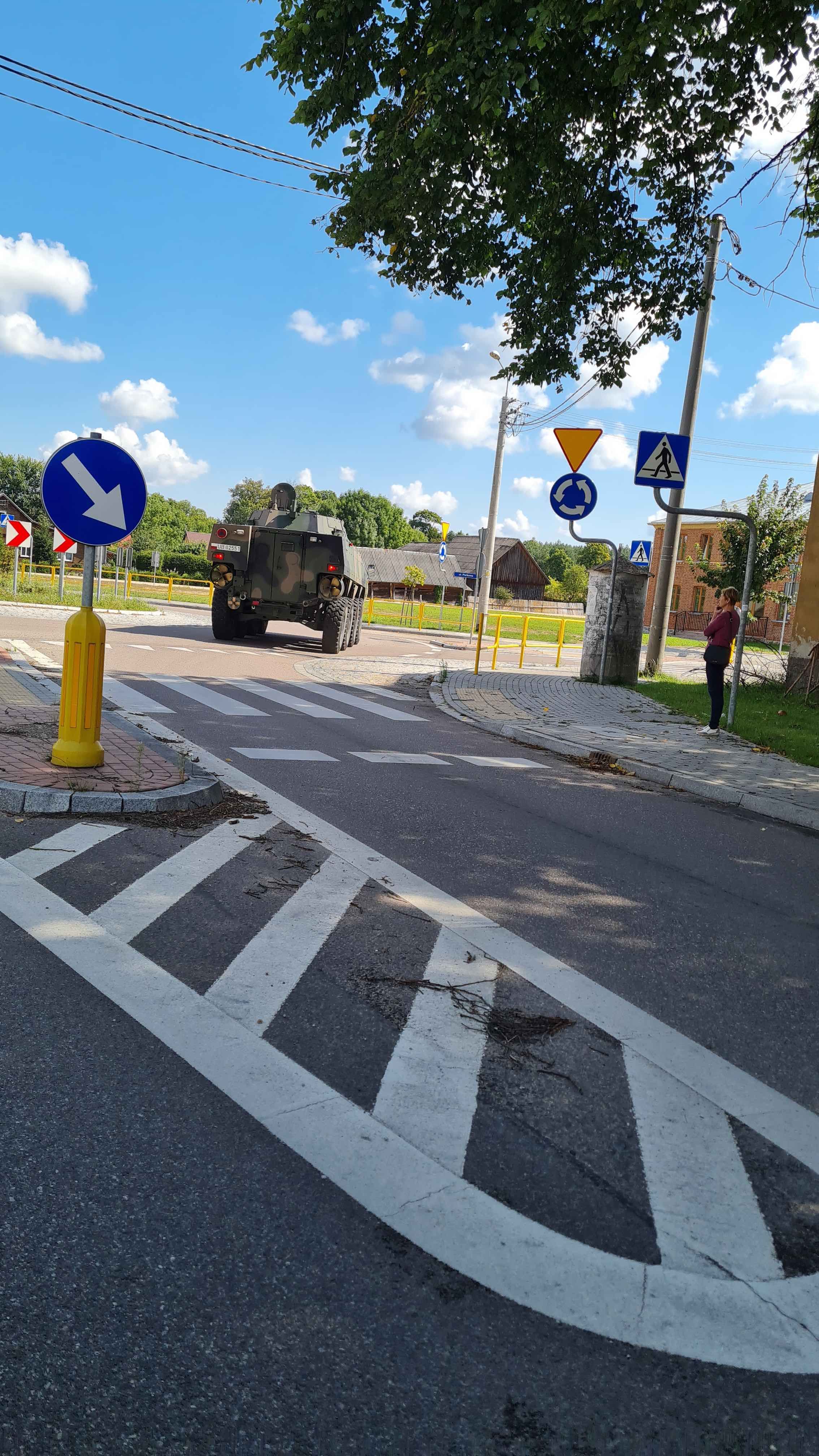 Transoorter wojskowy Rosomak jedzie przez wieś.