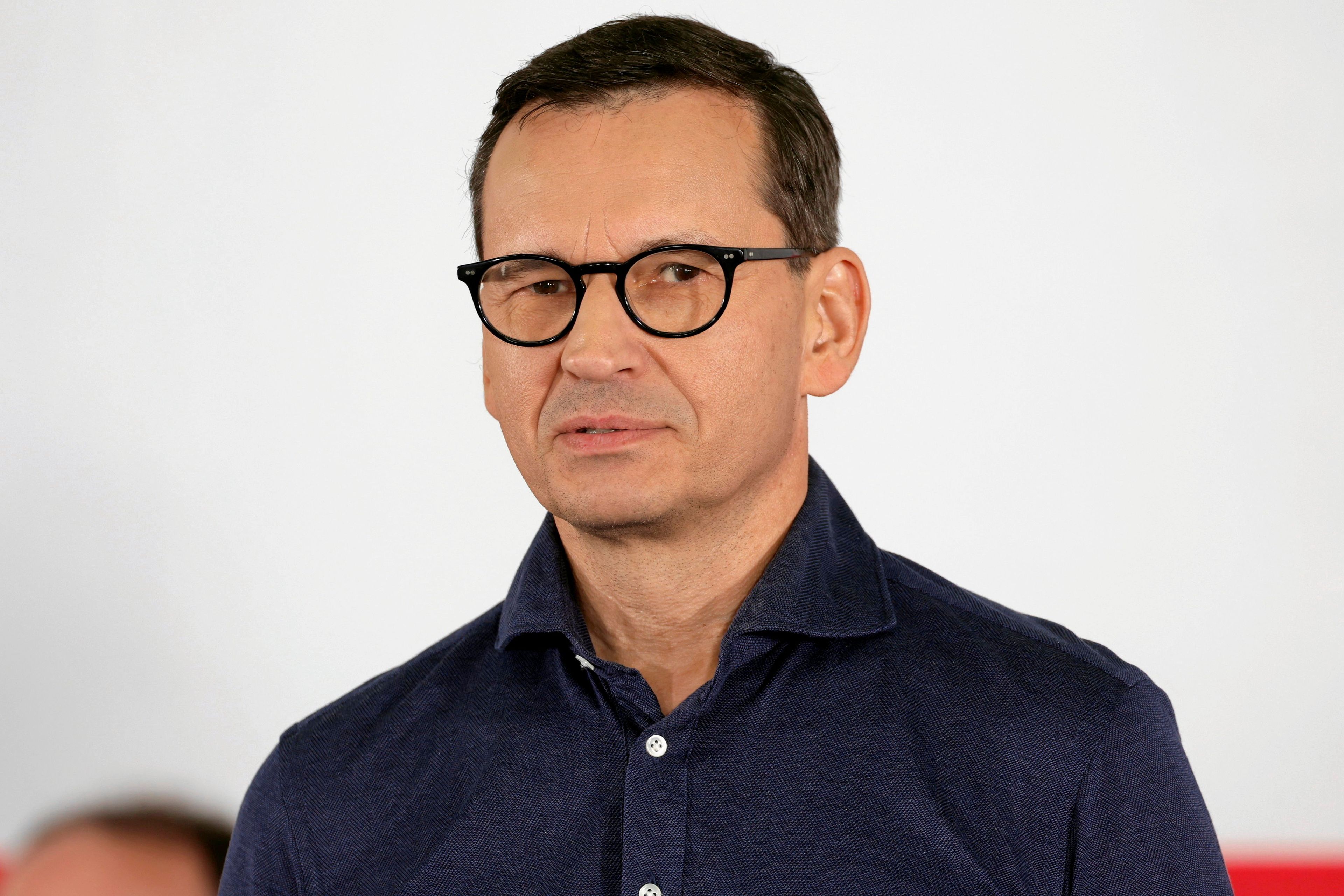 Mateusz Morawieckim na biało-szarym tle.