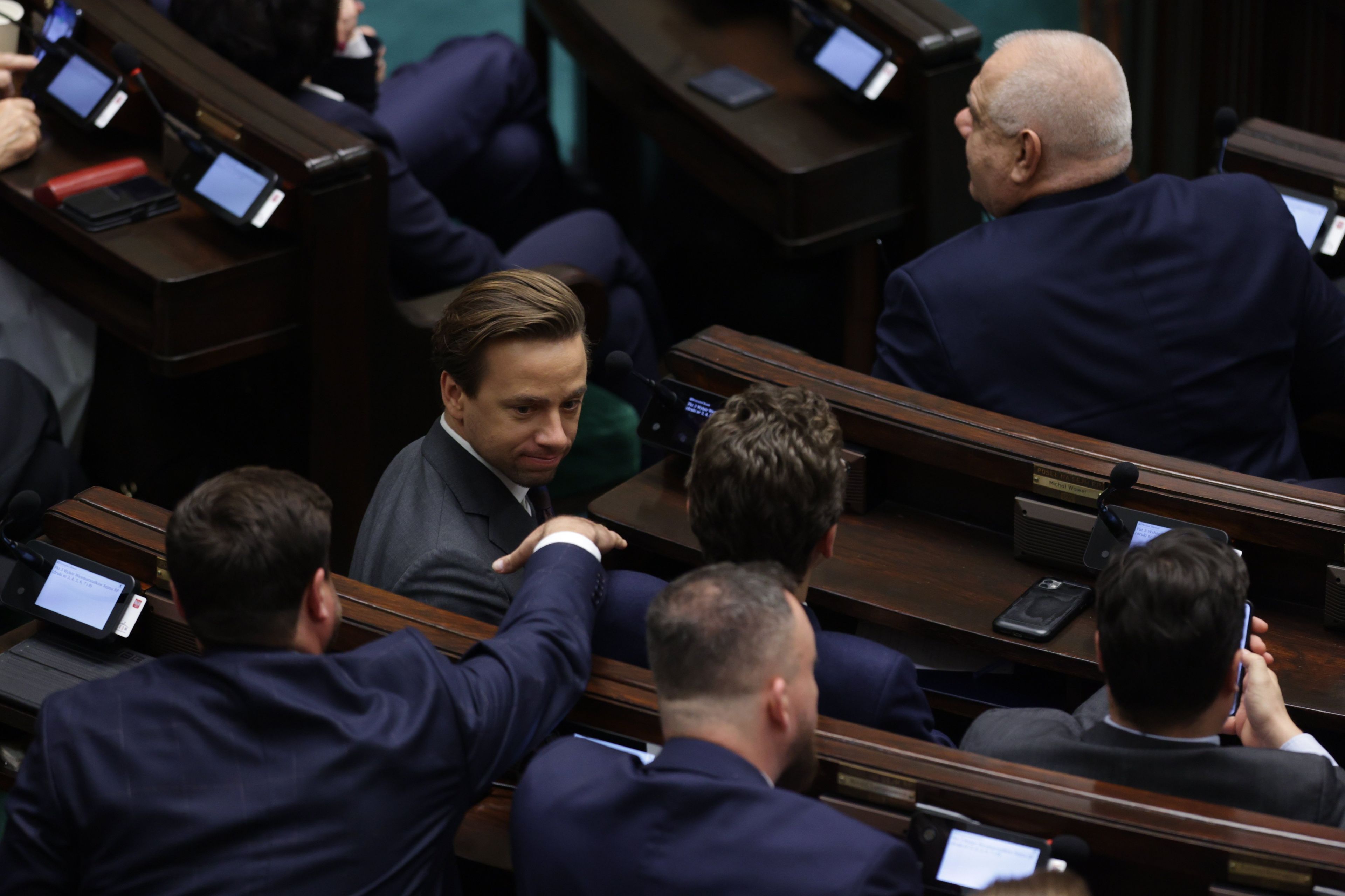 Poseł Konfederacji Krzytof Bosak odwraca się do swoich kolegów partyjnych w ławach sejmowych