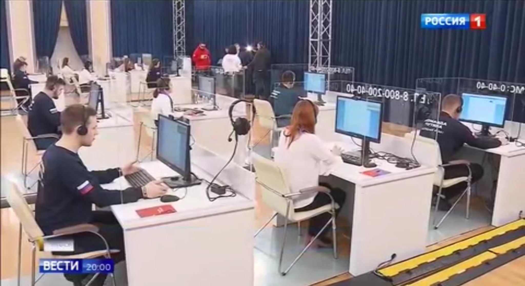 Młodzi ludzie przy ko puterach odbierają relefony w hali call canter. Na blizach mają rosyjski napis "Drużyna Putina"