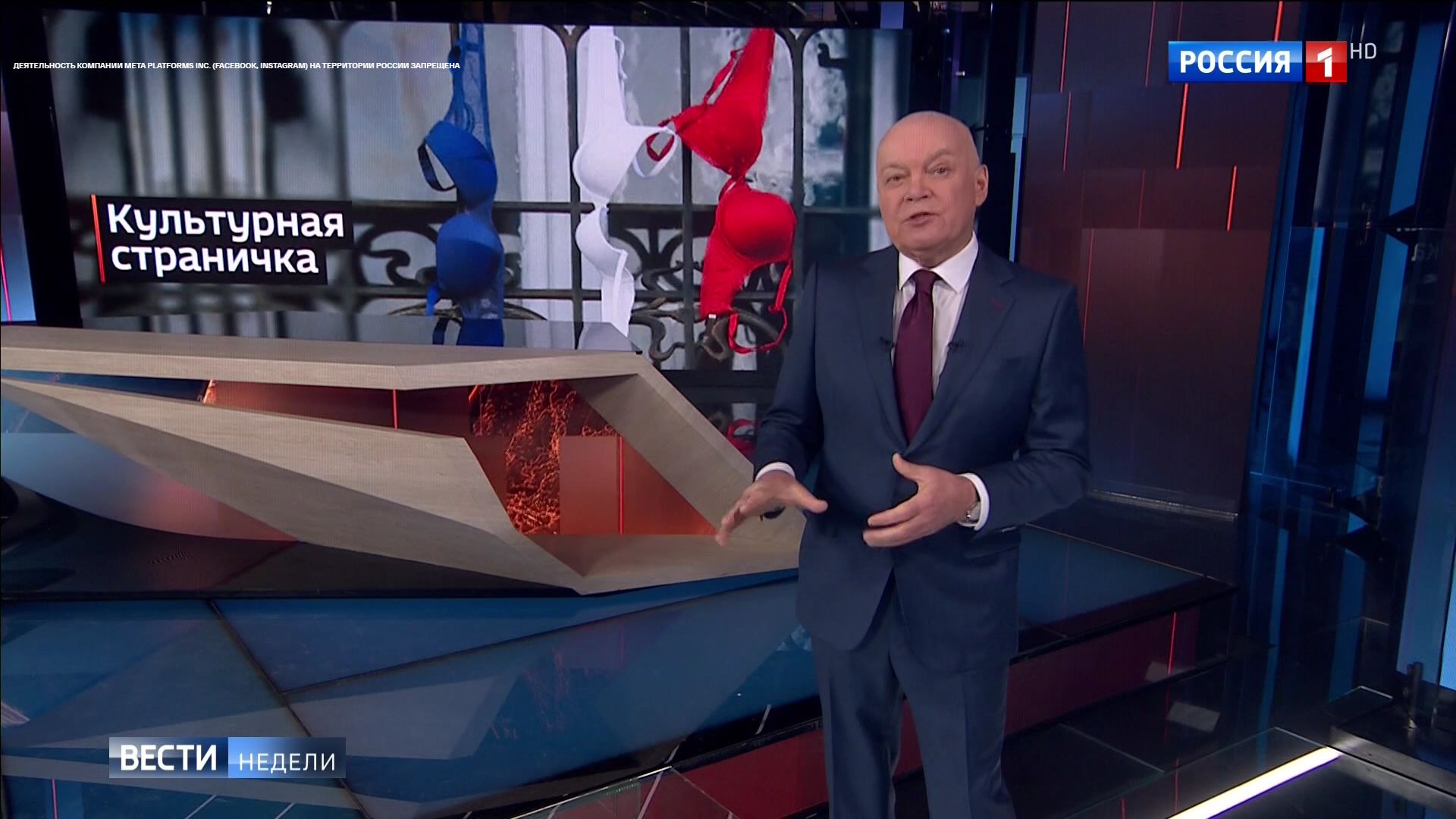 Starszy mężczyzna (Kisielow) stoi w studio na tle zdjęcia biustonoszy w barwach flagi Francji