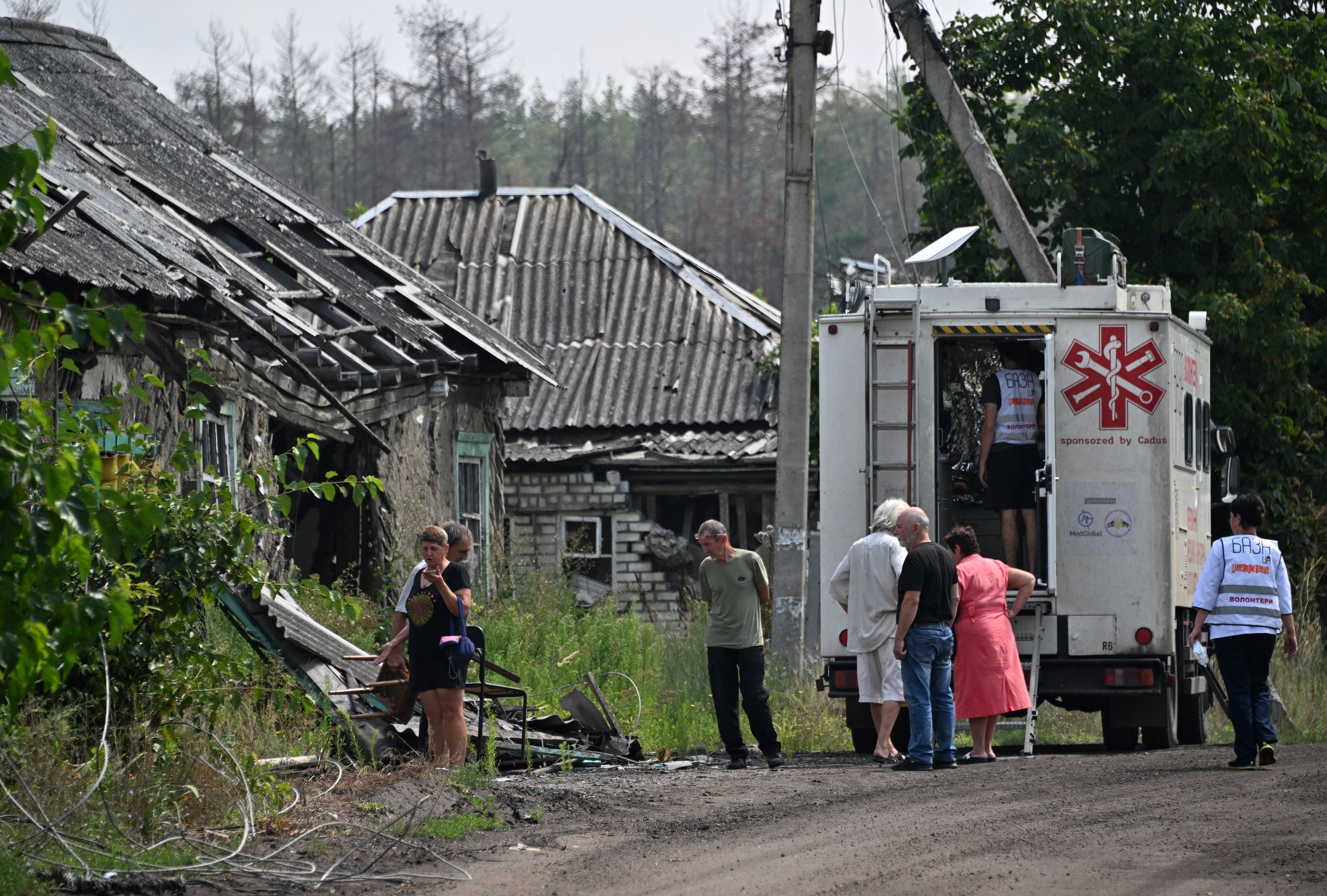 Residents wait for a medical examination outside a mobile hospital run by volunteer medics in the village of Staryi Karavan, Donetsk region on July 21, 2023, amid the Russian invasion of Ukraine. Many Ukrainian frontline villages have had no regular access to doctors or other basic services for more than a year. (Photo by Genya SAVILOV / AFP)
