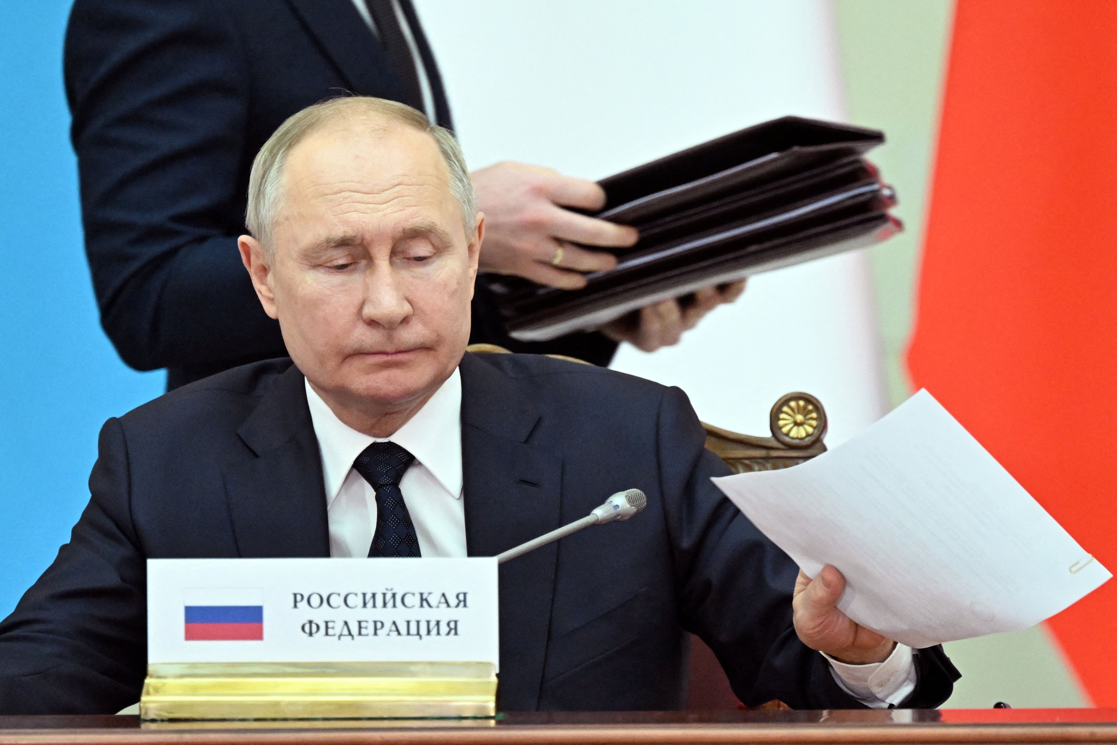 Władymir Putin, w tle człowiek z teczką