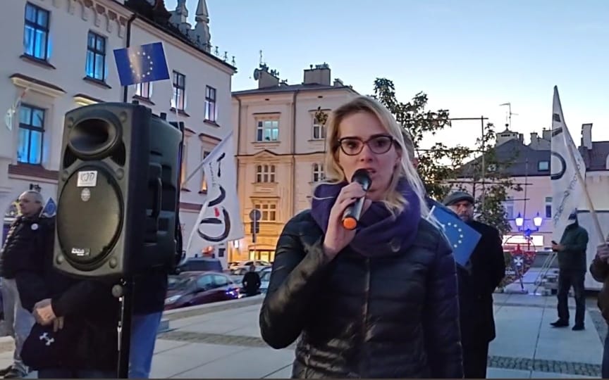 Kobueta na zabytkowym placu mówi do mikrofonu